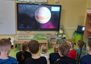 Dzieci oglądają film o planetach na dużym ekranie.
