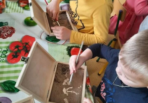 Dzieci odkopują kości dinozaurów.