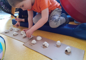 Chłopiec robi igloo z gliny.