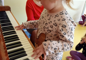 Dziewczynka próbuje grać na pianinie.