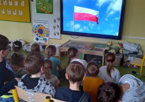 Dzieci oglądają na dużym ekranie film o fladze Polski.