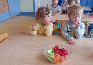 Drugie śniadanie - dzieci siedzą przy stołach i jedzą warzywa.
