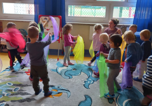 Warsztaty taneczne - dzieci machają kolorowymi chusteczkami w rytm muzyki.