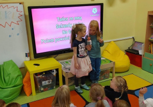 Dziewczynki śpiewają piosenkę na karaoke podczas dnia przedszkolaka.