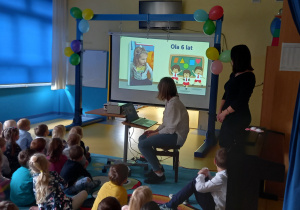 Duża grupa dzieci ogląda prezentację multimedialną z okazji Święta Edukacji Narodowej.