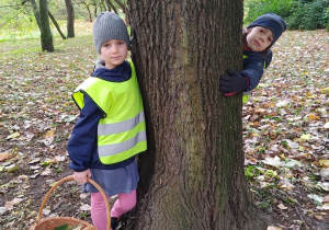 Dzieci przytulają się do drzewa w parku.