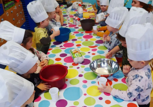 Dzieci w kucharskich kapeluszach przygotowują pancakesy.