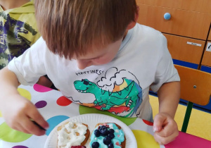 Dziecko ozdabia swoje pancakesy.