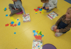 Dzieci na podłodze klasyfikują kształty.
