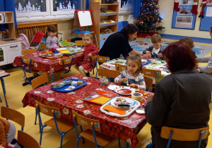 Warsztaty świąteczne. Dzieci i dorośli wykonują ozdoby świąteczne przy stolikach.