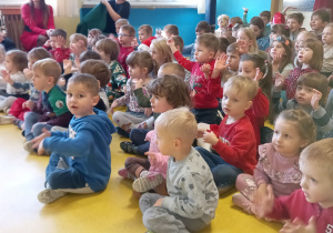 Dzieci siedzą na podłodze i czekają na świętego Mikołaja.