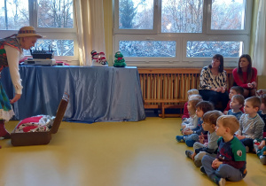 Dzieci siedzą na podłodze i oglądają świąteczne przedstawienie.