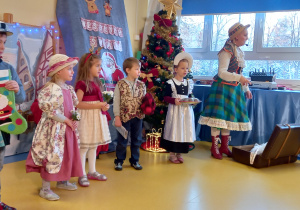 Dzieci stoją na scenie przebrane za przedwojennych Warszawiaków.