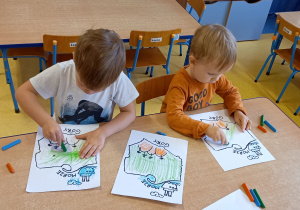 Dwaj chłopcy kolorują prosta mapę Polski.