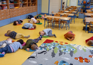 Dzieci leżą na na podłodze - udają sen zimowy niedźwiedzia.