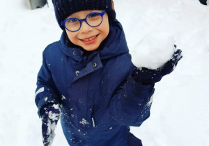Chłopiec pozuje ze śnieżką.