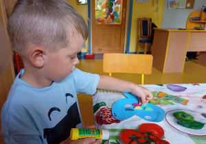Chłopiec wykonuje pracę plastyczną.