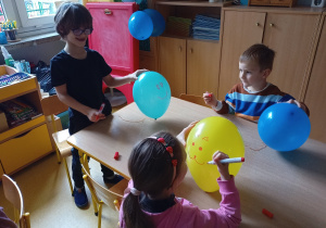 Dzieci ozdabiają balony z użyciem flamastrów.
