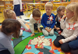 Dzieci układają puzzle z godłem Polski.