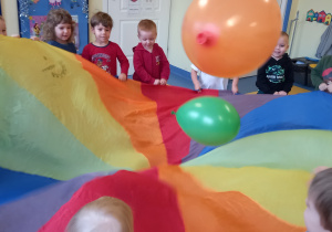 Dzieci podrzucają balony na kolorowej chuście.
