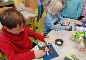 Chłopcy tworzą portrety dziadków z płyt CD.