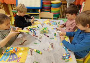 Dzieci wyklejają maski karnawałowe z papieru.