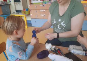 Nauczycielka pomaga dziewczynce zrobić kukiełkę ze skarpetki.
