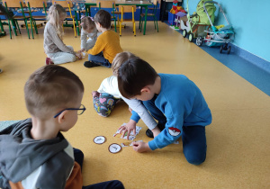 Dzieci układają puzzle z dinozaurami.