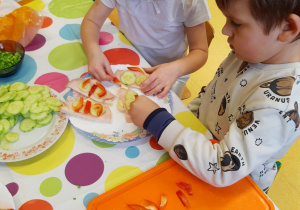 Dzieci ozdabiają przygotowane przez siebie kanapki warzywami.