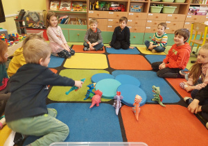 Dzieci rozwiązują zadanie matematyczne- ustalają ile jest dinozaurów przy wodopoju.