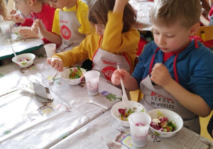 Warsztaty żywieniowe- dzieci robią sałatkę.