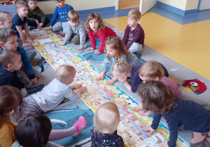 Dzieci oglądają książkę o bardzo długich kartkach.
