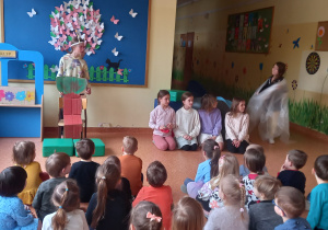 Dzieci oglądają przedstawienie w wykonaniu uczniów ze szkoły podstawowej.