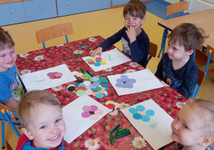 Dzieci ułożyły kształt kwiatka z kółek na białej kartce papieru.