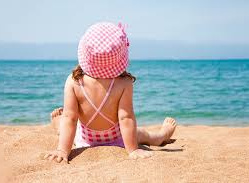 Dziewczynka w różowym kapeluszu siedząca na plaży
