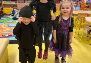 Troje dzieci przebrane w czarno - fioletowe stroje.
