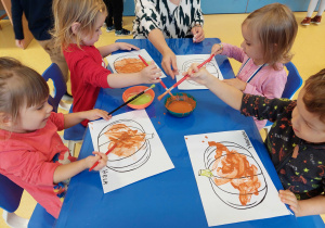 Dzieci malują szablon dyni puchnącymi farbami.