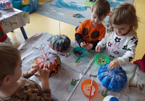 Dzieci ozdabiają cekinami wcześniej pomalowane dynie.