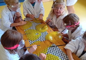 Dzieci wykonują eksperyment z żółtą cieczą.