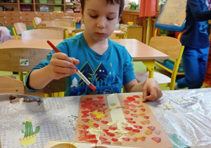 Dziecko maluje farbami plakatowymi w kolorach jesieni.