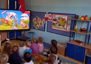 Dzieci oglądają na dużym ekranie film o symbolach narodowych.