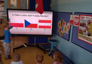 Chłopiec wskazuje flagę Polski na dużym ekranie.