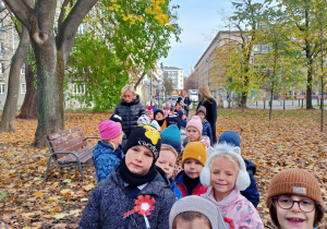 Grupa idzie przez park, by złożyć kwiaty przy pomniku walczących o wolną Polskę.