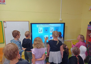Dzieci grają na tablicy interaktywnej podczas warsztatów antysmogowych.