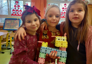 Dziewczynki pokazują pieska zbudowanego z klocków.