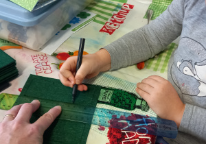 Dziecko rysuje planszę do gry w Kółko i krzyżyk na zielonym filcu.