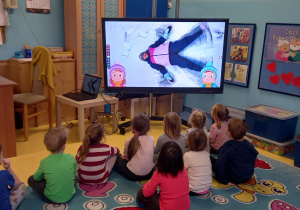 Dzieci oglądają pokaz zabaw zimowych na tablicy multimedialnej - aniołek.