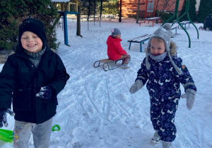Dzieci bawią się na śniegu na placu zabaw.