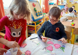 Dzieci malują serduszka z masy solnej.