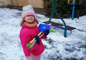 Dziewczynka pomaga w roznoszeniu łopatek do śniegu.